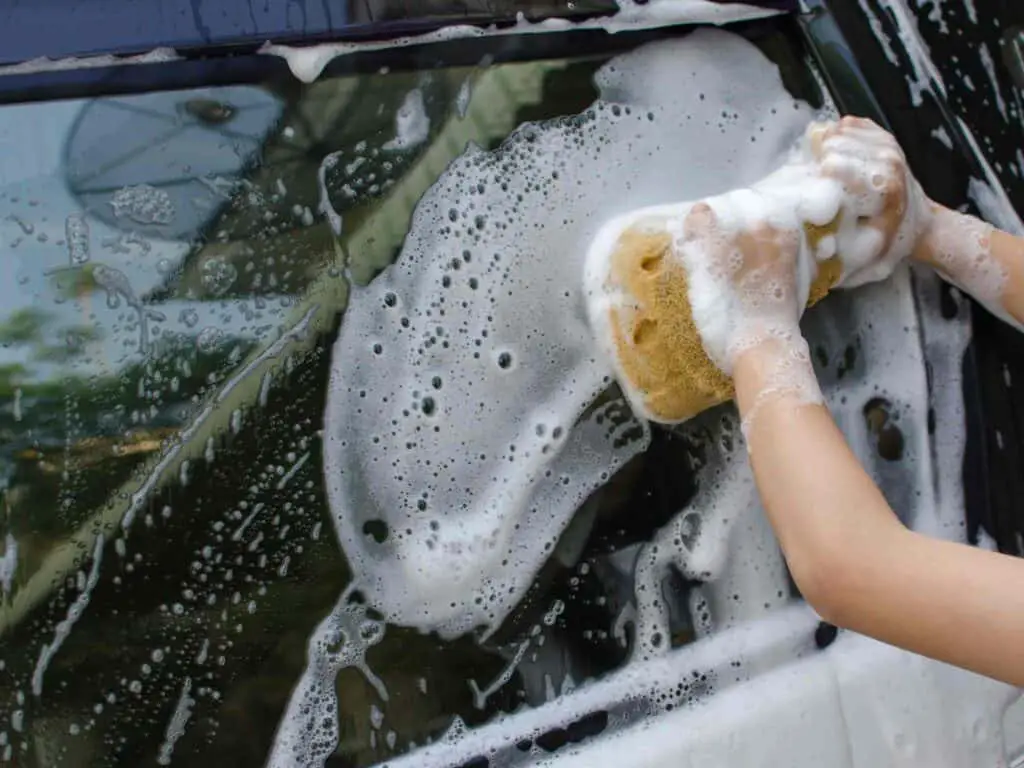 Eco-friendly car wash as one of the spring fundraising ideas for schools - in the pic a kid's hands seen washing a black car