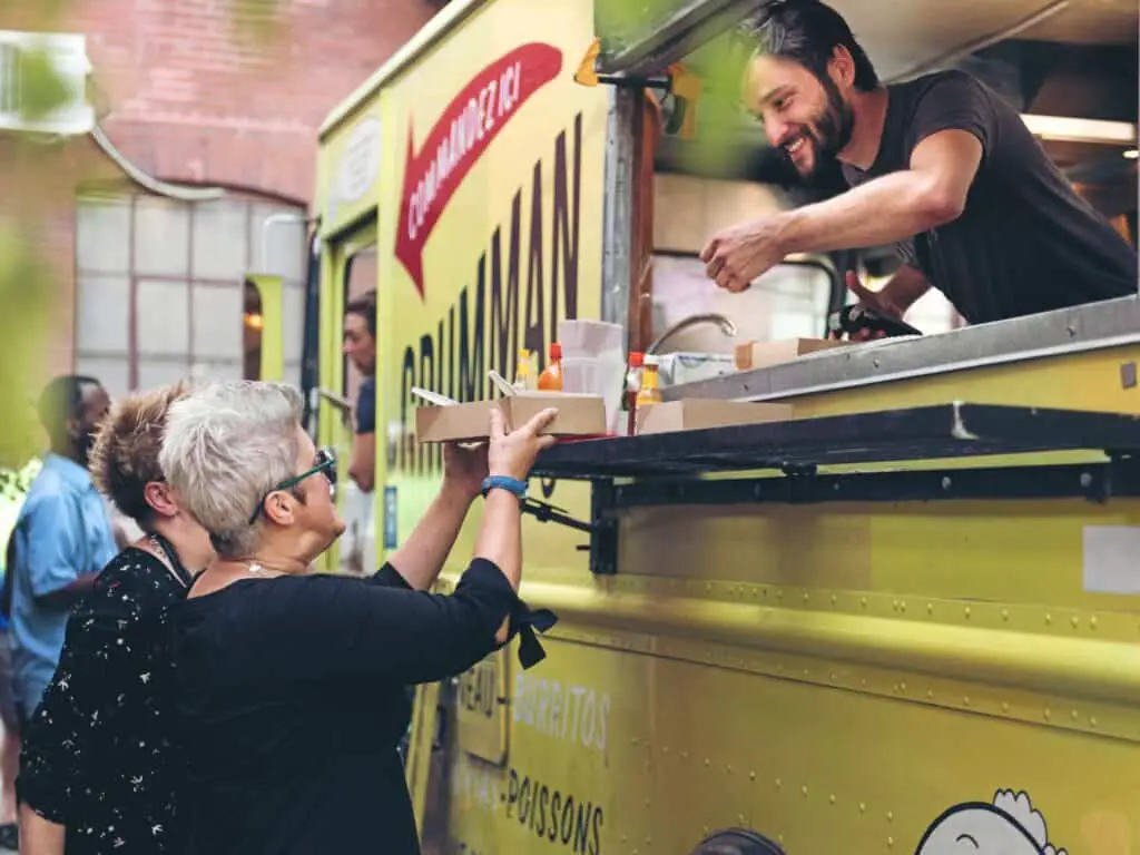man from food truck serving two ladies